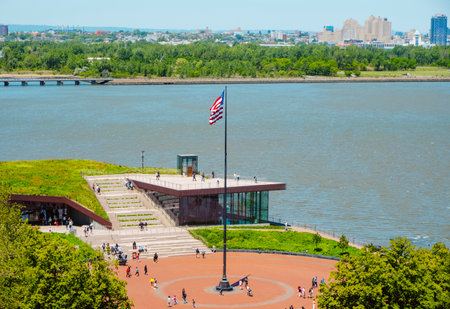 New York City, United States - May 17, 2023: A view of the Flagpole Plaza and the Statue of Liberty Museum, in Liberty Island, United States, with Jersey City in the backgroundのeditorial素材