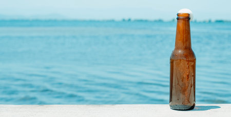 a bottle of refreshing beer on the pier, next to the water, in a panoramic format to use as web banner or headerの写真素材