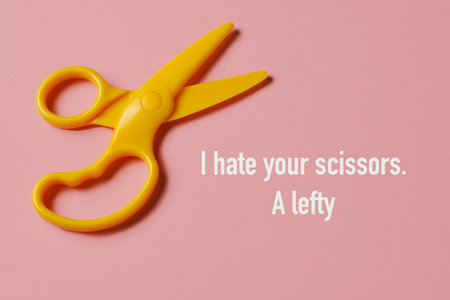 a pair of yellow plastic scissors for right-handed users and the text I hate your scissors, a lefty, on a pink backgroundの写真素材