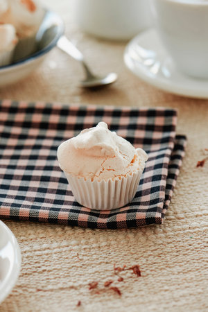 closeup of a spanish merengue almendrado, a baked meringues with almonds, on a checkered cloth placed on a table set with a brown tableclothの写真素材