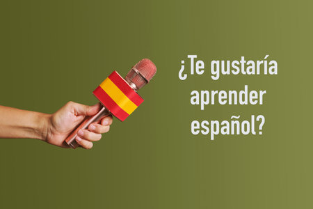 man holding a microphone patterned with the flag of spain and the question woud you like to learn spanish written in spanish on a green backgroundの写真素材
