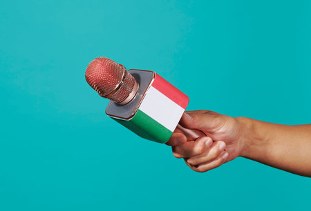 a man holds a microphone patterned with the italian flag against a blue backgroundの写真素材