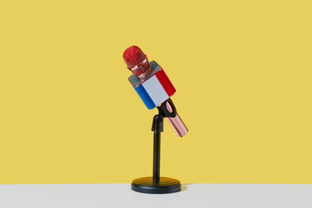a microphone patterned with the flag of france, in a black desktop stand placed on a white surface, in front of a yellow backgroundの写真素材