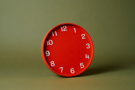 a red clock without any hands on an olive green backgroundの写真素材