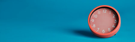 a pink clock without hands on a blue background with some blank space on the left, in a panoramic format to use as web bannerの写真素材