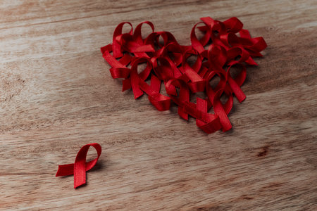 some red awareness ribbons, for the fight against AIDS, forming a heart on a wooden table