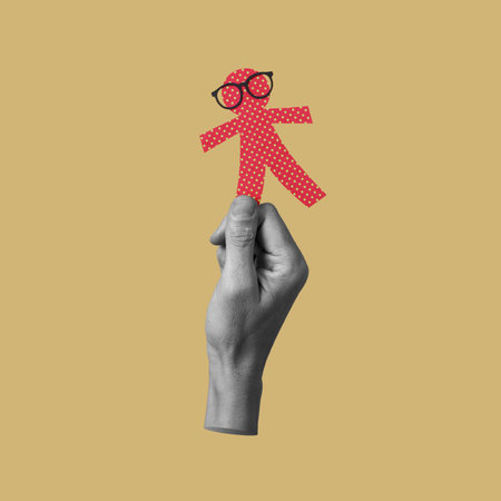 man holding a paper man doll, wearing eyeglasses, on an orangish yellow background, as a prank for the innocents day, a feast held in some countries equivalent to april fools dayの写真素材