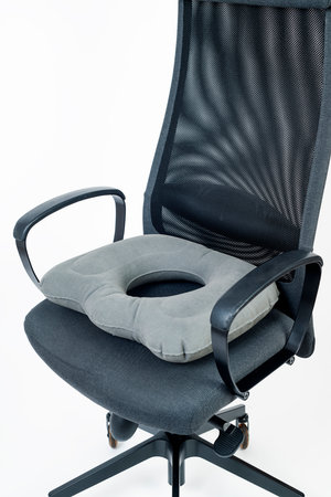 an inflatable ring cushion on an office chair, against a white backgroundの写真素材