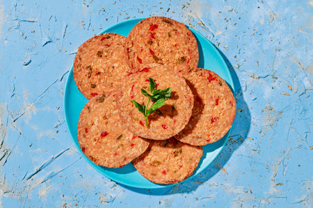 high angle view of a blue ceramic plate with some slices of a vegan roll with mushroom and pepper, placed on a blue rustic textured surfaceの写真素材