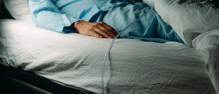 a man, in a blue pajamas, wears a urinary catheterization while is lying face up in bed, in a panoramic format to use as web bannerの写真素材