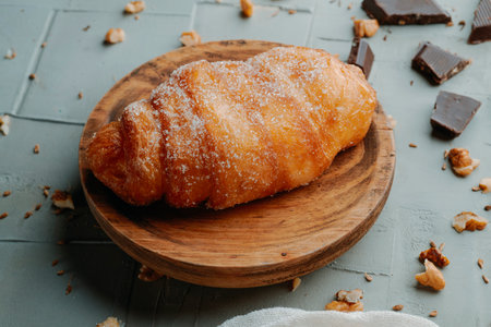 a xuixo de crema, a pastry filled with custard typical of catalonia, spain, on a wooden plate placed on a textured gray surfaceの写真素材