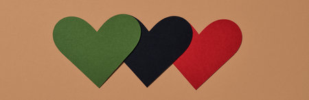 three hearts with the colors of the black liberation flag, green, black and red, on a brown background, in a panoramic format to use as web bannerの写真素材