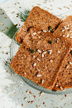 some slices of rye bread with flax seeds in a glass plate, on a gray textured surface