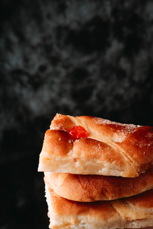 a stack of some pieces of catalan coca de sant joan, typical of catalonia, spain, and traditionality eaten on saint johns eve, in front of a dark backgroundの写真素材