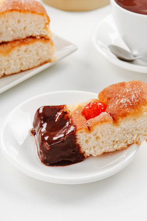 closeup of a piece of catalan coca de sant joan, typical of catalonia, spain, dipped in hot chocolate, on a white tableの写真素材
