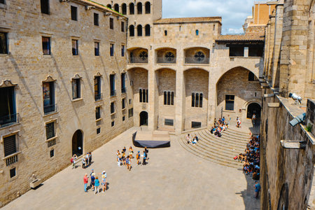 Barcelona, Spain - June 4, 2024: Tourists in Placa del Rei square, in Barcelona, surrounded by important landmarks, as Palau Reial Major palace in the center and Capella de Santa Agata on the rightのeditorial素材