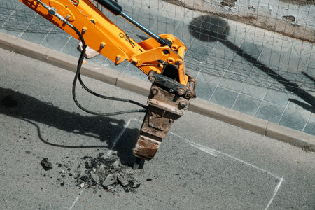 closeup of an hydraulic jackhammer mounted on an excavator being used to break up the asphaltの写真素材