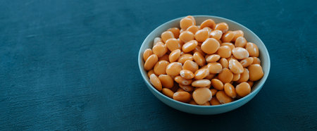 some spanish altramuces, lupinus albus beans, cooked and pickled in brine, typically eaten as snack, in a bowl on a rustic surface, in a panoramic format to use as web banner or headerの写真素材