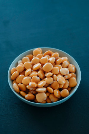 closeup of a blue ceramic bowl with some spanish altramuces, lupinus albus beans, cooked and pickled in brine, typically eaten as snack, on a dark greenish gray rustic surfaceの写真素材
