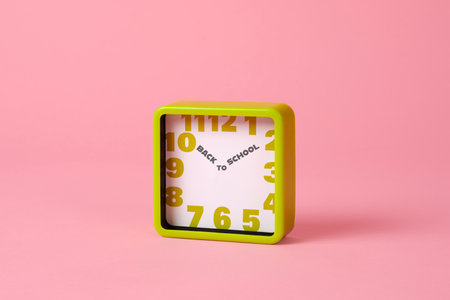a green square clock, with the text back to school written instead of the hour and the minute hands, on a pink background with some blank space aroundの写真素材