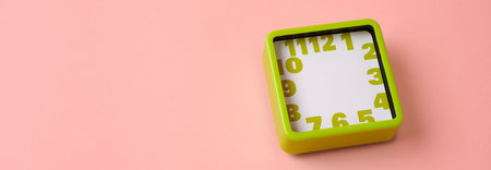 a green square clock, with no hour or minute hands, placed on a pink background with some blank space on the left, in a panoramic format to use as web banner or headerの写真素材