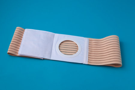an unfolded abdominal belt with a stoma opening for colostomy patients on a blue backgroundの写真素材