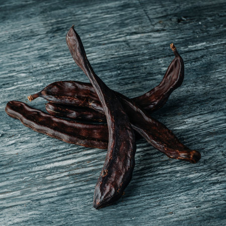 closeup of some ripe carob pods on a gray rustic wooden tableの写真素材