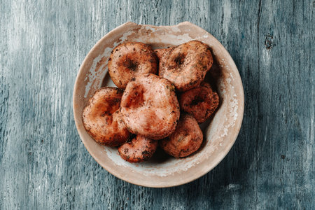 high angle view of a rustic white ceramic plate with some raw rovellons, typical autumn mushrooms highly appreciated in Catalonia, Spain, on a gray wooden tableの写真素材