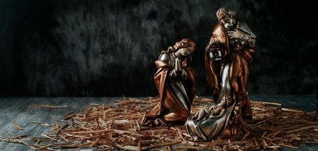 the holy family, saint joseph, the virgin mary and the baby jesus, on the straw, on a dark background, in a panoramic format to use as web bannerの写真素材