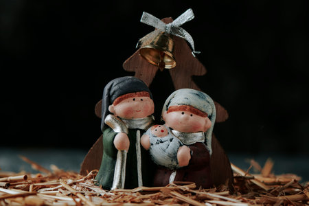 a nice and childish depiction of the holy family, formed by saint joseph and the virgin mary with the child jesus in her arms, on a gray wooden surface, in front of a black backgroundの写真素材