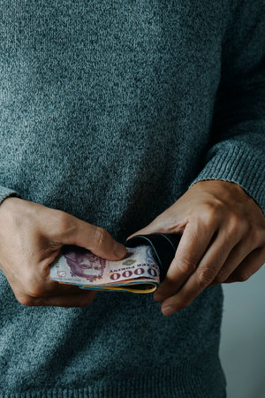 a man takes out or puts some hungarian forint bills into his wallet, indoorsの写真素材
