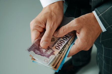 closeup of a businessman, in an elegant gray suit, with some hungarian forint notes standing indoorsの写真素材