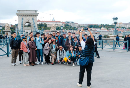 Budapest, Hungary - October 5, 2024: A group of tourists are photographed at the Szechenyi Chain Bridge, in Budapest, Hungary, which connects Pest with Buda, in the other side of the Danube Riverのeditorial素材