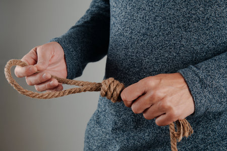 closeup of a man holding a jute rope with a noose in front of a gray backgroundの写真素材