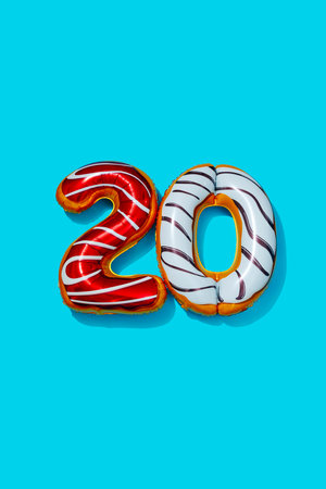 a pair of foil balloons of different colors and patterns forming the number 20 on a blue backgroundの写真素材