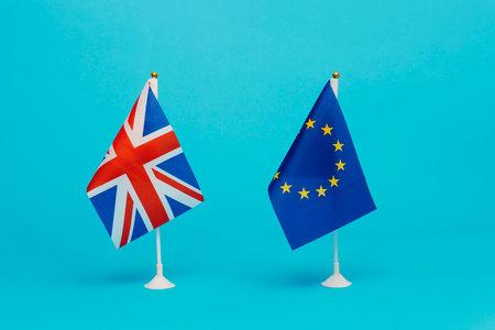 the flag of the United Kingdom and the flag of the European Union standing side by side on a blue...