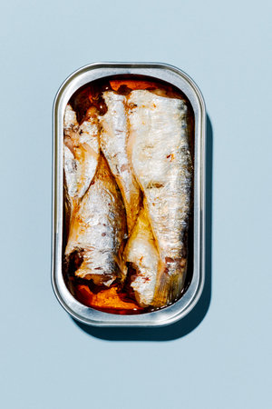 high angle view of an open can of canned sardines on a light blue backgroundの写真素材