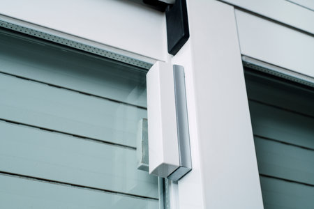 closeup of a wireless glass break detector and contact breaker on a window, as part of a burglar alarm systemの写真素材