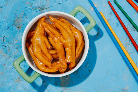 high angle view of a pale green ceramic casserole with some asian boneless chicken feet coated in...