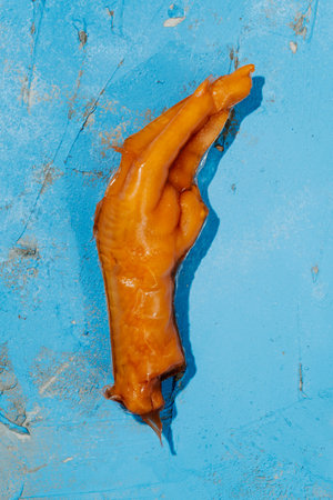 high angle view of an asian boneless chicken foot coated in gelatin placed on a blue rustic textured surfaceの写真素材