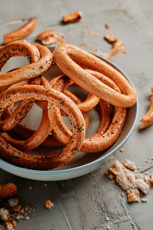 a closeup of a plate with some covrigi, romanian bread rings, sprinkled with poppy seeds, placed on...