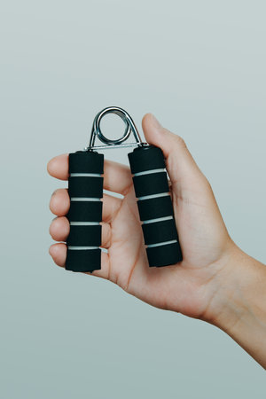 human hand gripping an exercise tool in front of a light gray backdropの写真素材