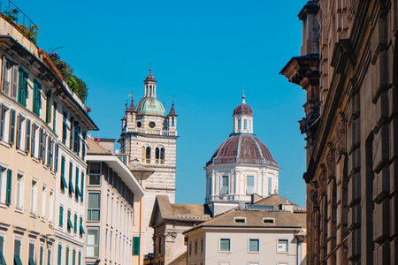 a view the striped bell tower and the dome of Cathedral of San Lorenzo in Genoa, Italy, seen from a lively street in the historic centerの写真素材