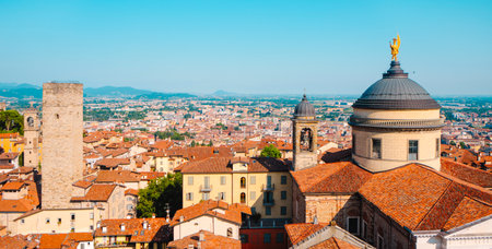 view over the rooftops of the Citta Alta in Bergamo, Italy, showing the dome of Sant Alessandro Cathedral, a bell tower and the stone Torre del Gombito against the cityscapeの写真素材