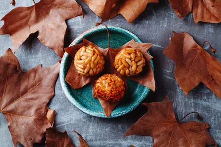 high angle view of an autumn leaf in a plate holding various Catalan panellets with pine nuts and...