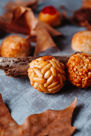 closeup of traditional Catalan panellets eaten for All Saints Day, featuring the classic pine nut version beside others made with chopped almonds and candied cherryの写真素材