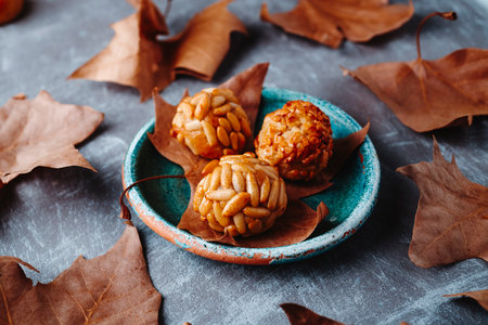 Catalan panellets arranged on a rustic ceramic plate with dry autumn leaves, almond and pine nut sweets made for All Saints Day in Catalonia, Spainの写真素材
