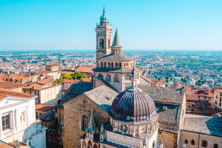 aerial view of the Basilica di Santa Maria Maggiore and the Cappella Colleoni in Bergamo Alta, Italy, their domes and towers rising above the terracotta rooftops and the city belowの写真素材