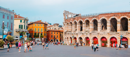 Verona, Italy - June 23, 2025: Crowds move across the wide piazza in front of the Arena di Verona as bright facades and cafes create a vibrant summer scene full of casual activityのeditorial素材