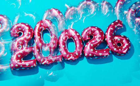 pink heart patterned balloons shaping 2026, as the new year, create a dynamic kaleidoscopic effect as their repeated reflections pulse across a vivid blue surface in shifting distorted formsの写真素材